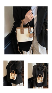 Detail of cream leather bucket bag with brown trim, logo text, and heart charm accessory