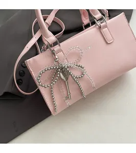 Close-up of pink shoulder bag featuring a stylish bow and vintage key charm detail