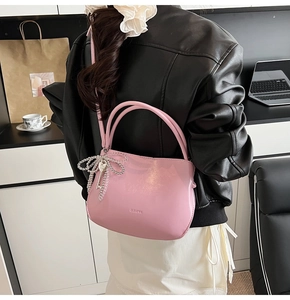 Détail du sac seau rose brillant avec nœud en perles argentées et pendentif clé