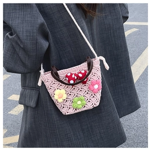 Close-up of pink crochet mini bag with 3D floral accents and a red polka dot bow