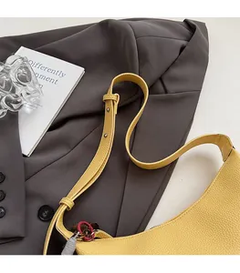 Détail de la bandoulière réglable avec rivets argentés sur un sac en cuir jaune