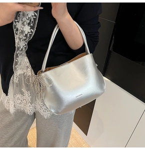 Détail d'un sac seau argenté métallique avec un charmant nœud en perles et une poignée