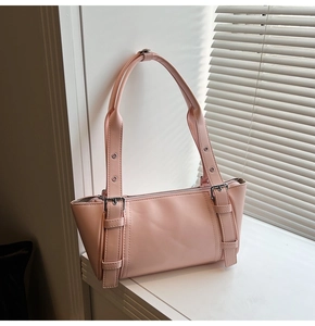 Détail du sac sous le bras rose clair avec boucles décoratives et fini cuir mat