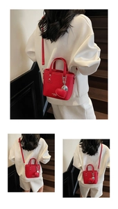Detail of red bucket bag with litchi texture, golden logo, and heart-shaped pendant detail