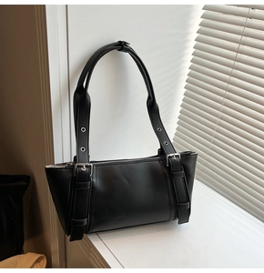Détail du sac sous l'aisselle noir avec boucles argentées et coutures verticales épurées