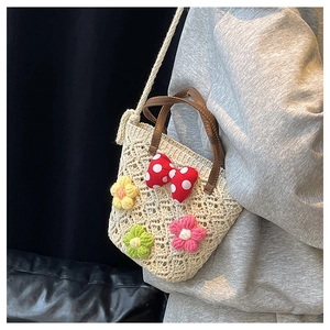 Detail of woven beach bag with crochet flowers and red polka dot bow decoration