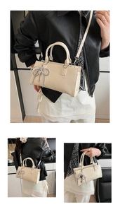 Detail of cream white leather Boston bag with silver bow charm and crossbody strap