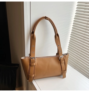 Détail d'un sac bandoulière en cuir camel chaud avec boucle argentée et design moderne