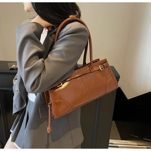 Detail view of caramel brown glossy leather shoulder bag with side buckle and double straps