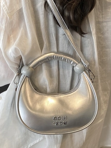 Silver metallic crescent handbag with round handle and metal logo lettering in front
