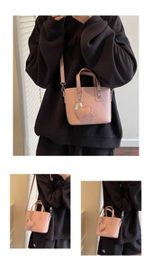 Detail of pink bucket bag with heart pendant and gold logo on textured leather