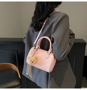 Detail of pink pebbled leather Boston bag with plush bear charm and ribbon accent