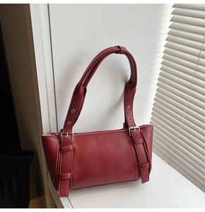 Détail du sac sous le bras en cuir bordeaux avec boucles argentées et œillets