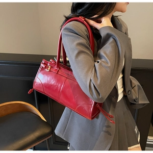 Side view of a vintage red patent leather shoulder bag worn by a model in style