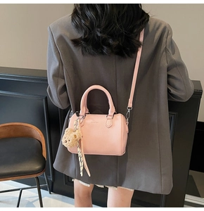 Close-up of pink cylinder handbag with litchi texture and cute bear charm detail