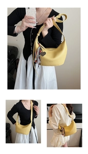 Détail du sac hobo jaune en cuir grainé avec pompon coloré et breloque en forme de cœur