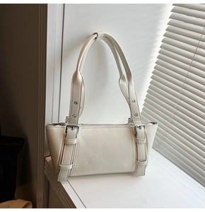 Détail du sac sous l'aisselle en cuir crème avec sangles décoratives et fini mat
