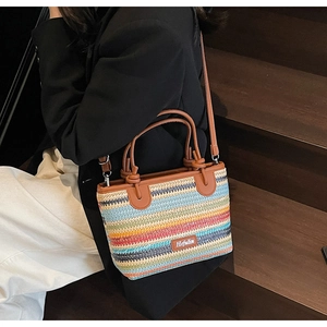 Dettaglio borsa tessuta a righe colorate con manici in pelle marrone ed etichetta
