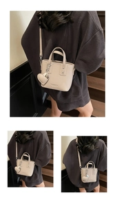 Detail of beige bucket bag with lychee texture leather and heart pendant accessory