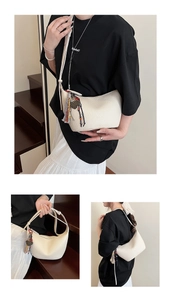 Détail du sac croissant crème en cuir grainé avec pompons et bandoulière réglable
