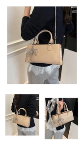 Detail of cream baguette bag with crystal bow charm and silver metallic brand logo