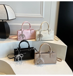 Detailed view of structured leather handbags in multiple colors with bow-knot charms
