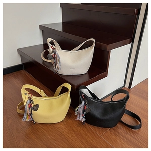 Trois sacs bandoulière demi-lune en beige, jaune et noir avec glands et pendentif cœur