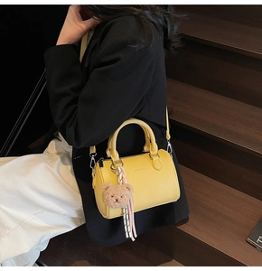 Detail view of yellow lychee grain leather mini boston bag with cute bear charm and tassel