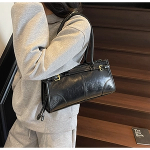 Detail of vintage black leather shoulder bag with gold buckle and pleated texture detail