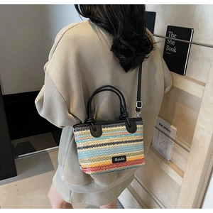 Dettaglio della borsa a secchiello in tessuto a righe multicolori con manico in pelle nera