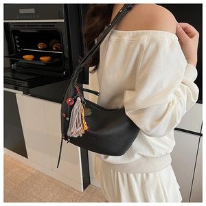 Détail du sac hobo en cuir grainé noir avec glands colorés et breloques en perles
