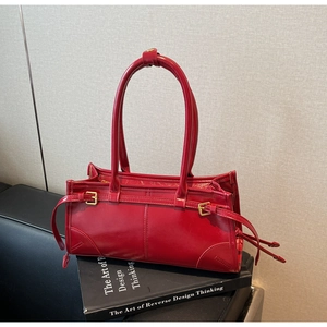 Detail of red faux leather shoulder bag with vintage metallic buckles and tassel accents