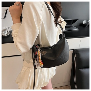 Détail du sac croissant noir grainé avec franges multicolores et pendentif cœur