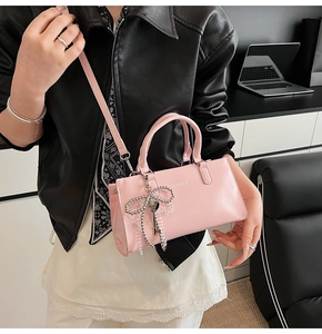 Close-up of pink shiny PU leather baguette bag with silver bow and key charms