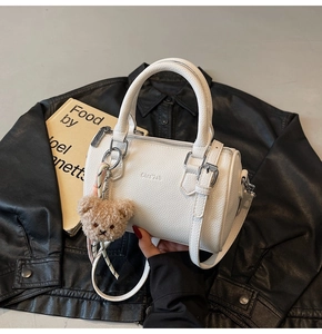 Close-up of white pebble leather cylinder bag with cute plush bear charm detail