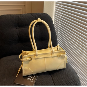 Detail of cream pleated shoulder bag with metallic buckle and stitching on blue velvet