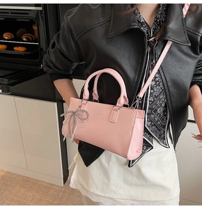 Detailed macro view of the pink PU leather handbag with a silver bow charm attachment