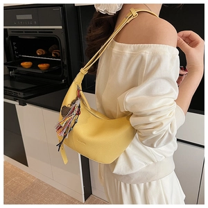 Détail du sac hobo jaune en cuir grainé avec pompon coloré et breloque en perles