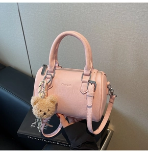 Detailed close-up of pink lychee leather texture and bear charm on Boston handbag