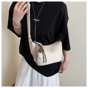 Détail du sac demi-lune en cuir grainé blanc crème avec pompon et pendentif coeur