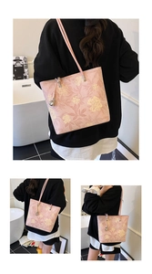 Detailed macro view of pink floral leather tote bag with silver ball pendant and long strap