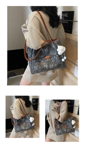 Detail view of floral canvas tote bag with brown woven straps and white plush cloud charm