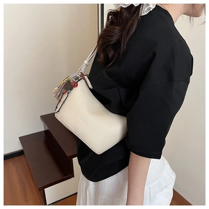 Détail du sac en cuir grainé crème avec des glands colorés de style ethnique et perles