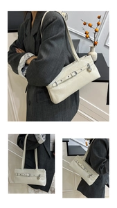 Detail of cream white faux leather shoulder bag featuring silver buckle and heart charm