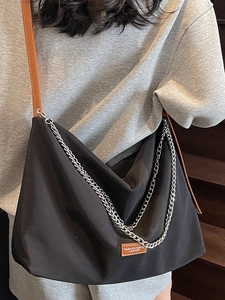 Black large capacity shoulder bag with silver chains and brown leather strap on model