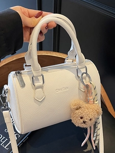 White textured leather Boston bag with a mini plush bear charm and adjustable strap