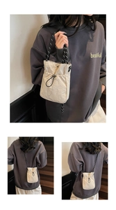 Detail showing the beige nylon drawstring crossbody bag with woven straps on a model