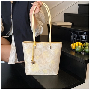 Detail of floral bucket bag with long handles and a golden sphere charm on leather