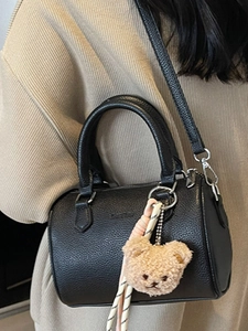 Chic black lychee grain cylinder bag with dual handles and a cute bear charm pendant