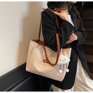 Detail of beige jacquard tote bag with woven brown handle and cute cloud charm accessory